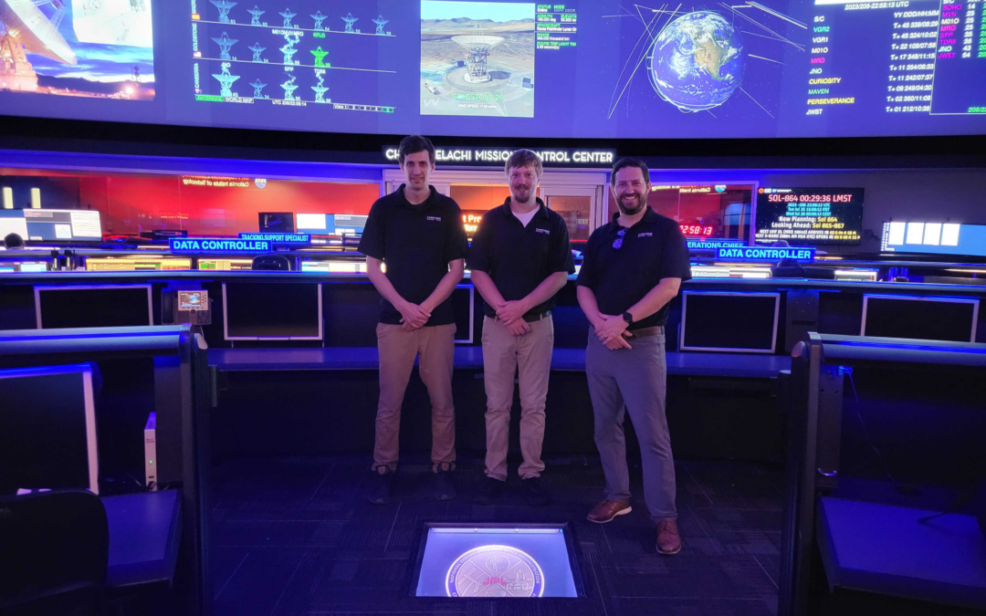 Bradley Cheetham, Alec Forsman, and Ethan Kayser stand in the middle of JPL Mission Control